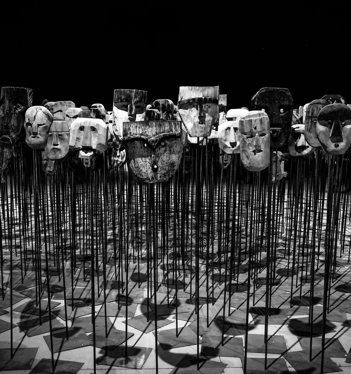 greyscale photo of masks on a stick