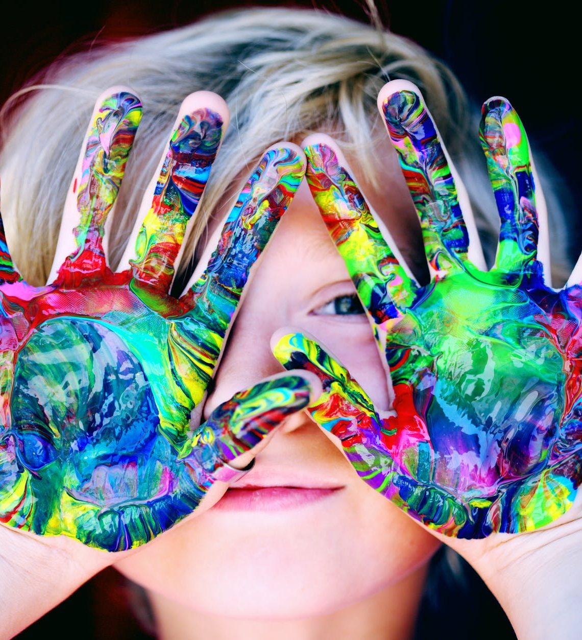 a kid with multicolored hand paint