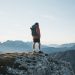 unrecognizable traveler standing on mountain top and admiring landscape