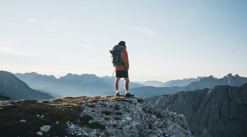unrecognizable traveler standing on mountain top and admiring landscape